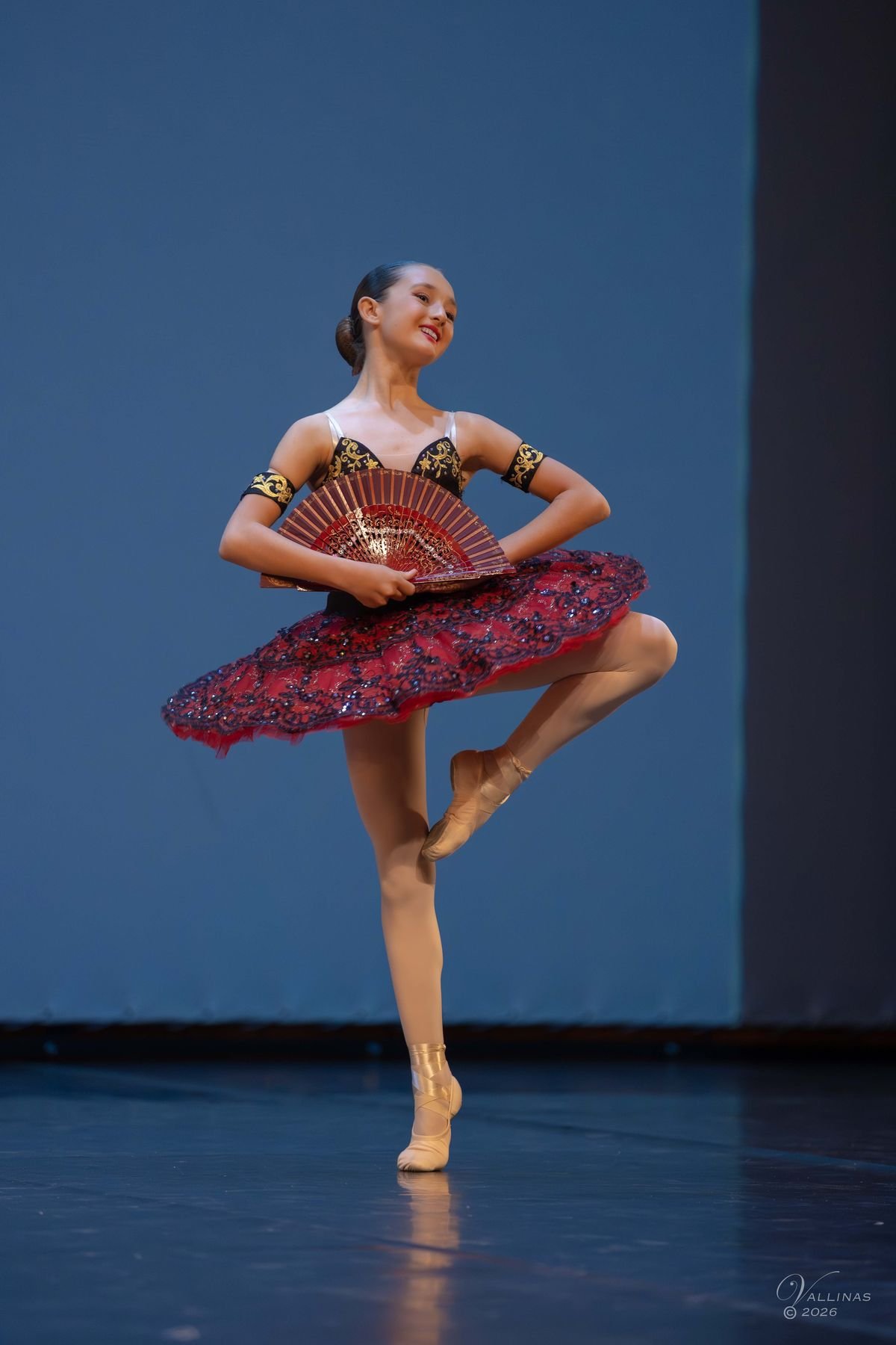 Bailarina con tutú rojo y abanico en pose sobre puntas