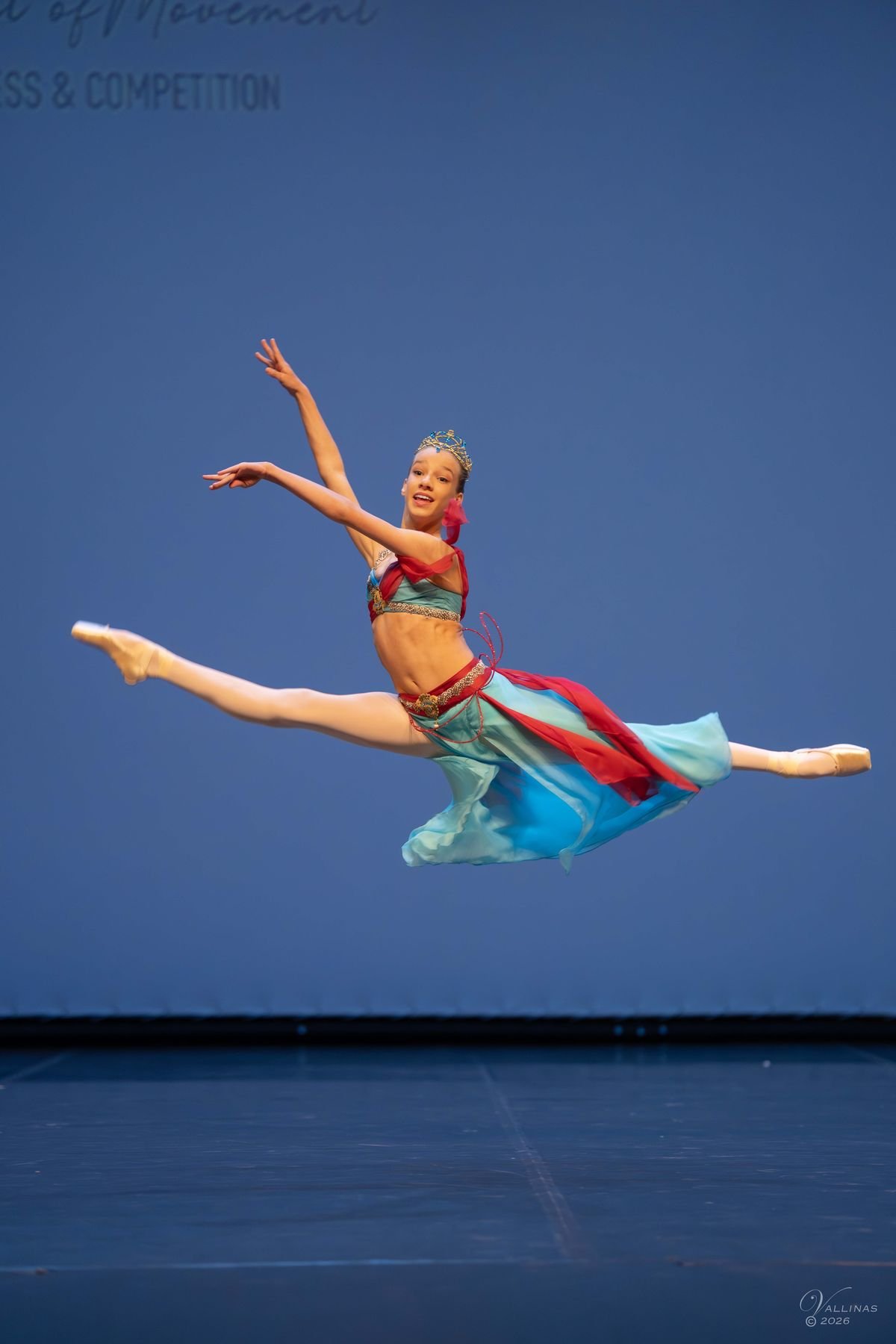 Bailarina con vestido azul y rojo en un gran salto