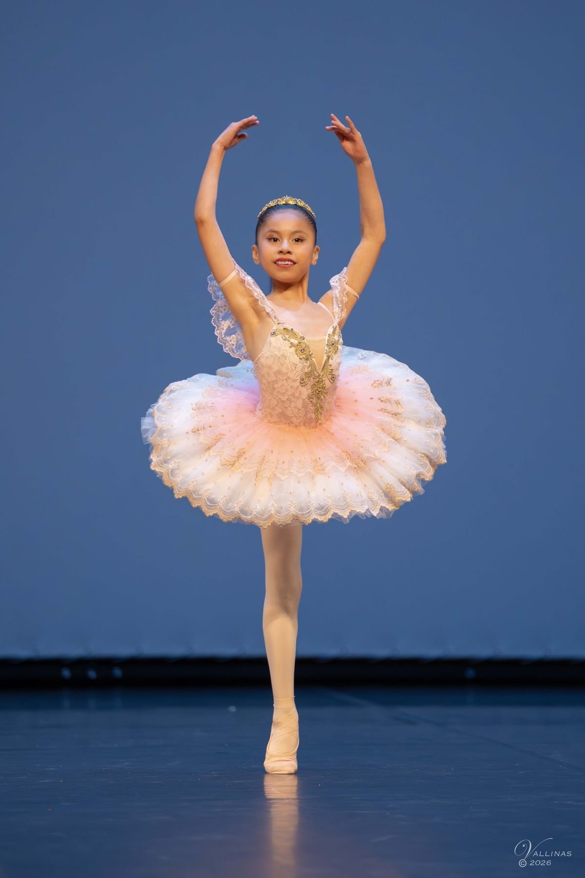 Bailarina con tutú en posición de brazos en quinta sobre el escenario
