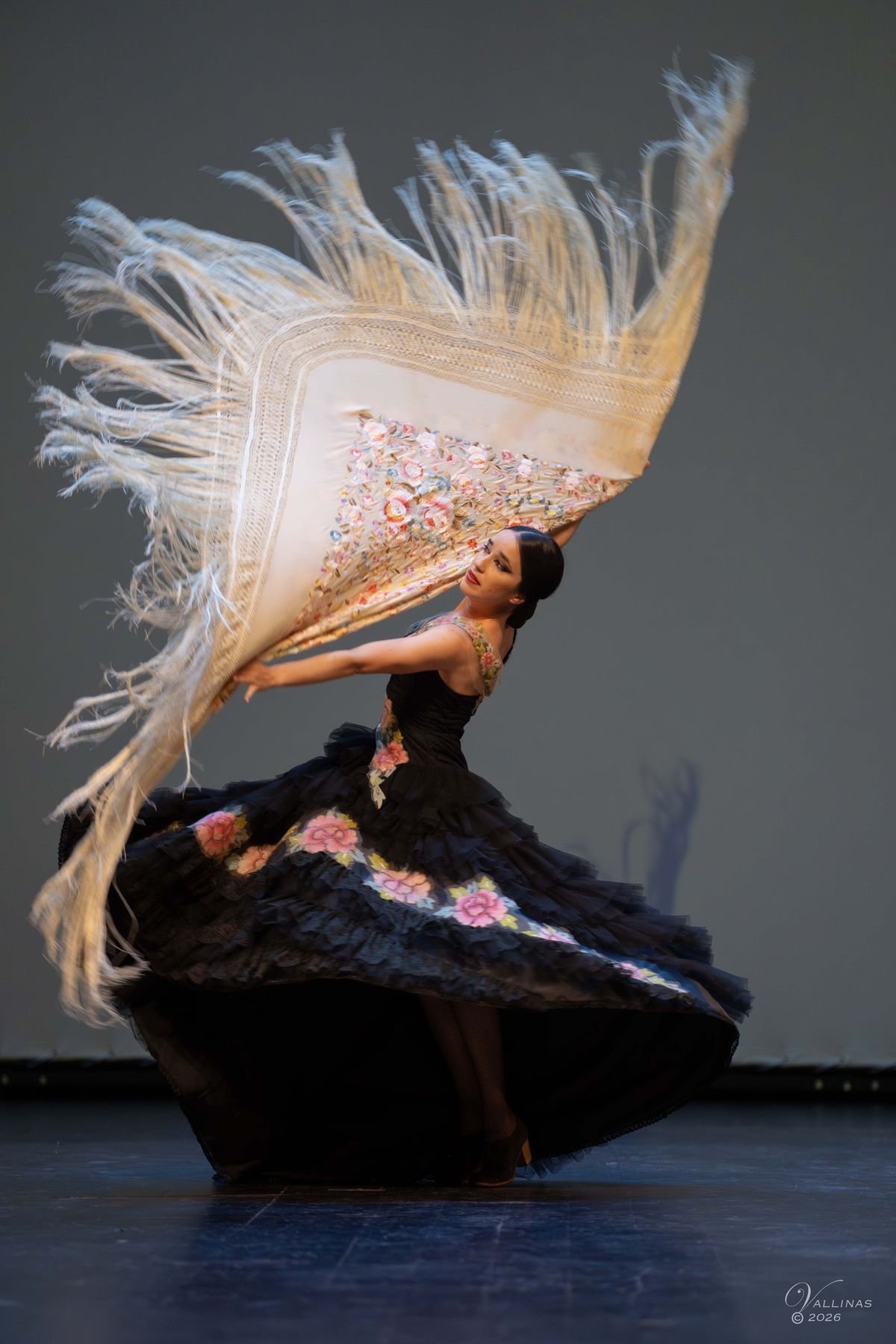 Bailarina de español girando con un mantón de flecos blancos en el aire