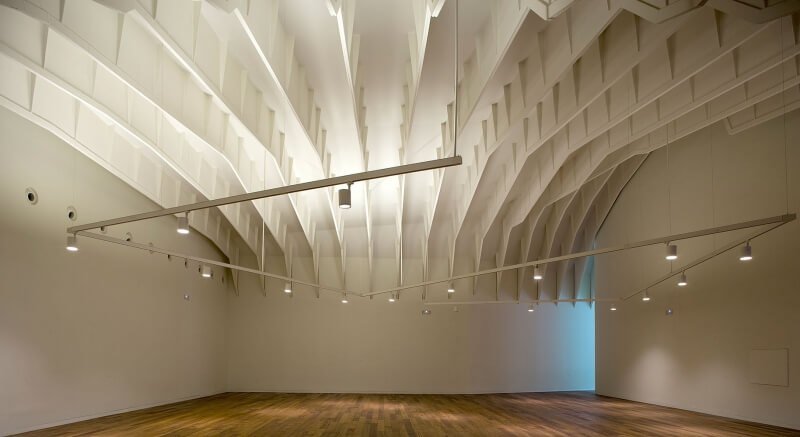 Sala diáfana de Lienzo Norte con suelo de madera y techo de vigas blancas
